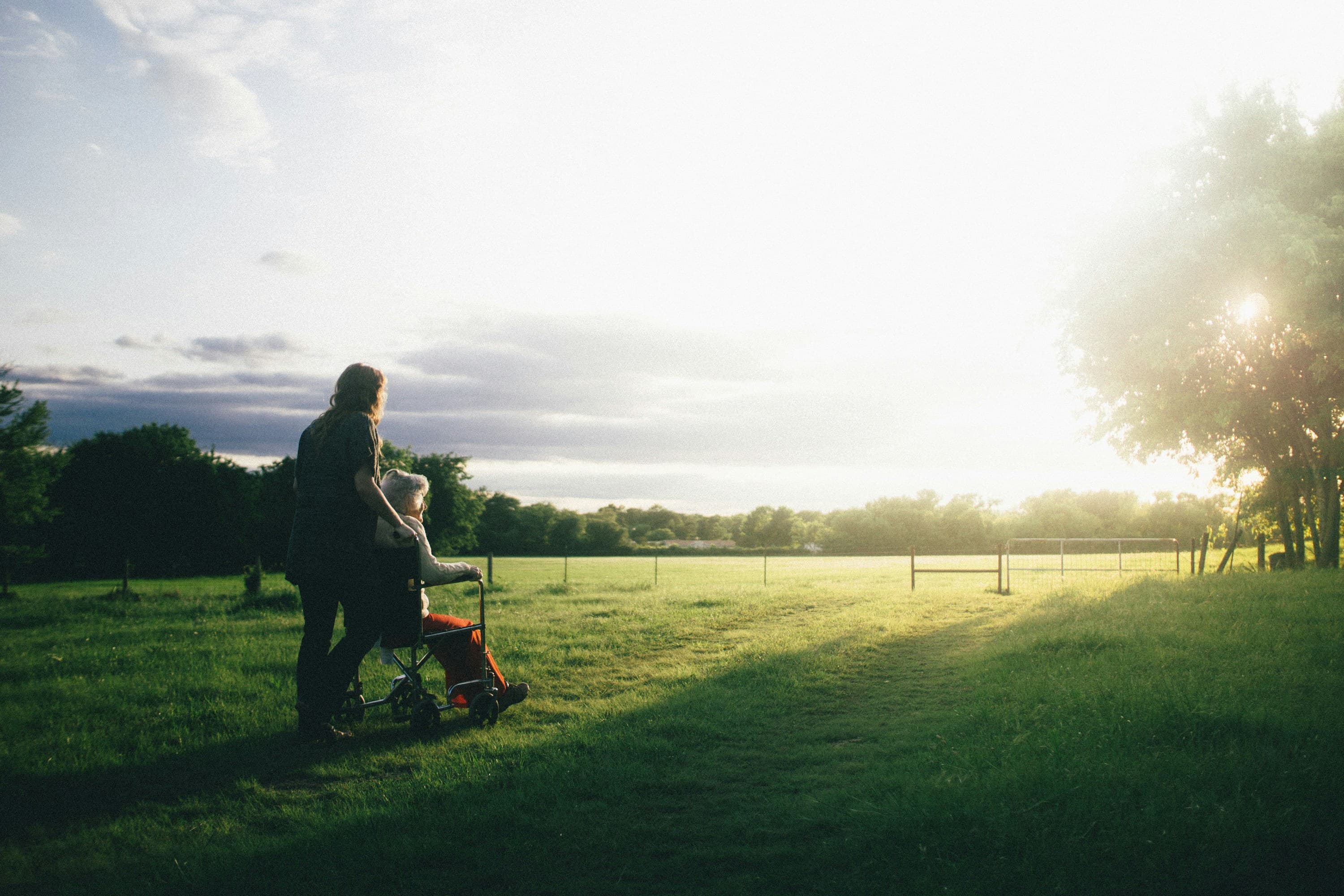 A daughter walking with her grandmother through a sunlit field